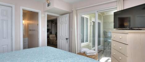 Une chambre à coucher comprenant un lit, une télévision, une commode et un ventilateur de plafond.