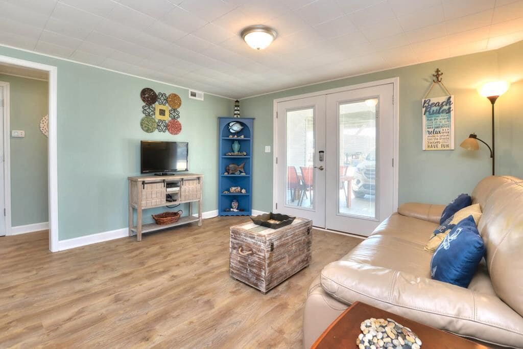 A living room with a sofa, a television, a coffee table, and a decorative wall piece.