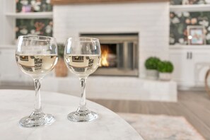 Twee glazen witte wijn op een marmeren tafel, met een open haard op de achtergrond.