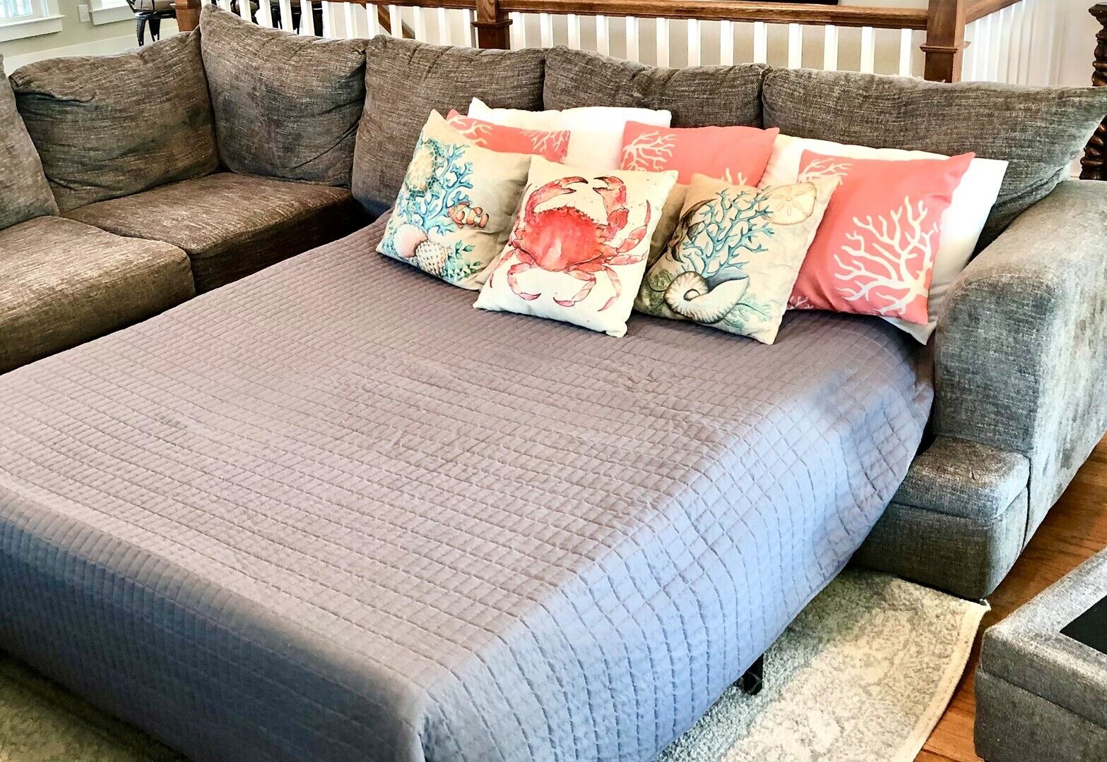 Un canapé modulable recouvert d’un tissu matelassé gris, agrémenté de coussins décoratifs aux motifs marins.
