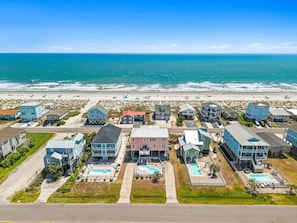 A coastal residential area with houses, a beach, and a clear view of the ocean. - Island Treasure: Ocean View home with Private Pool (Oak Island)