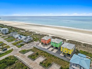 A coastal residential area with houses near the beach, a wooden deck, and a clear view of the ocean.