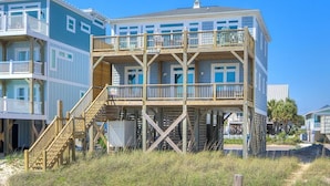 A multi-story beachfront building with wooden balconies and a staircase leading to the upper levels. - Oceans Eleven 03: Stunning 5BR oceanfront home in Oak Island, perfect for families! (Oak Island)