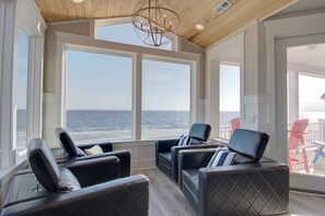A sunroom with large windows, leather chairs, and a wooden ceiling. - Oceanfront Suite Dreams in Oak Island with 8 bedrooms and stunning views. (Oak Island)