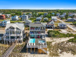 A beachfront house with a large deck, a swimming pool, and multiple levels.