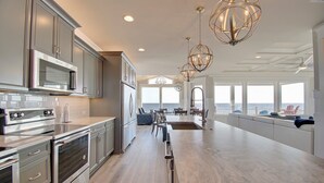 A modern kitchen with stainless steel appliances, a large island, and a view of the ocean.