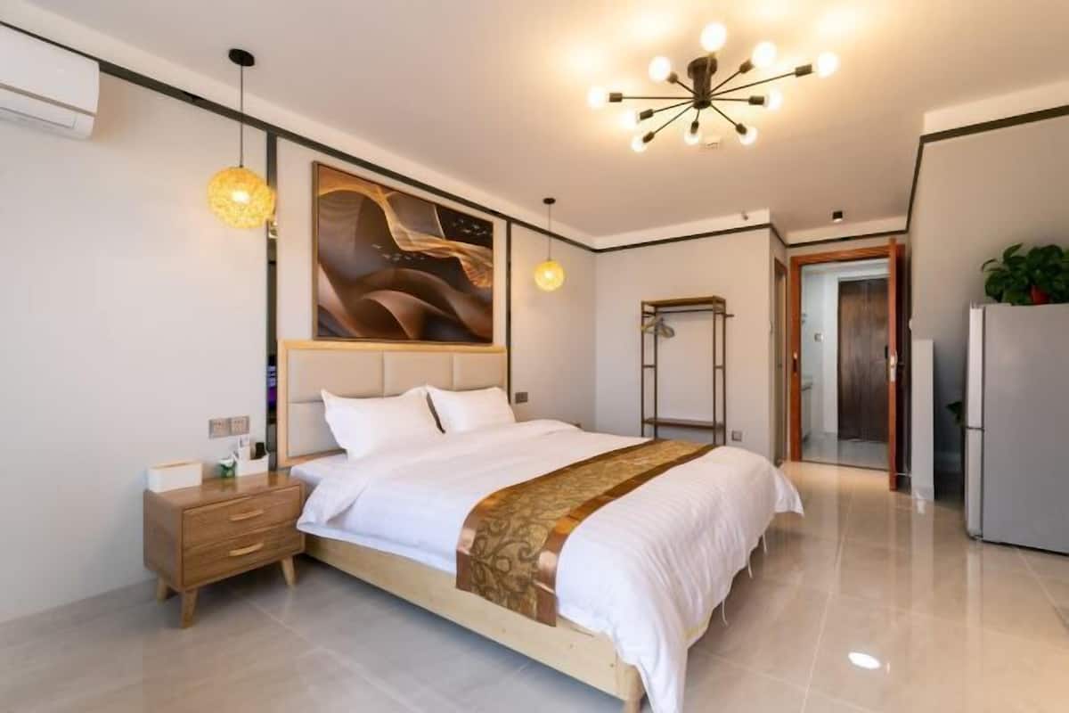 A modern bedroom with a large bed, bedside tables, a wardrobe, and a ceiling light fixture.