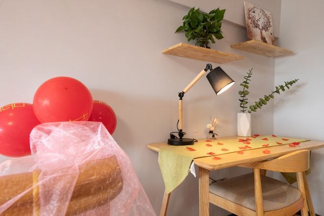 Ein Zimmer mit Schreibtisch, Stuhl, Lampe, Topfpflanze und Luftballons.