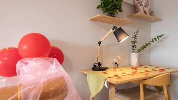 Ein Zimmer mit Schreibtisch, Stuhl, Lampe, Topfpflanze und Luftballons.