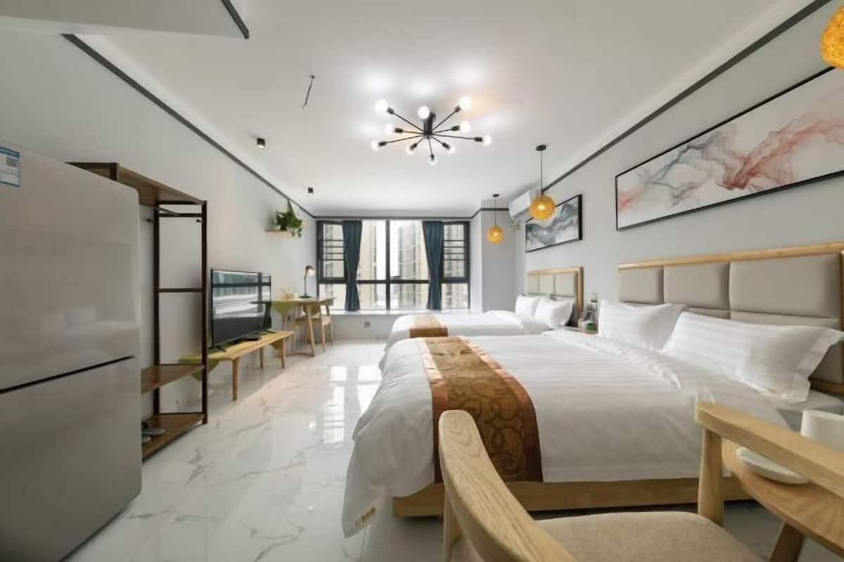A modern hotel room with a large bed, a desk, a television, and a refrigerator.