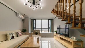 Ein modernes Wohnzimmer mit einer Couch, einem Holztisch, einem Fernseher und einer Treppe.