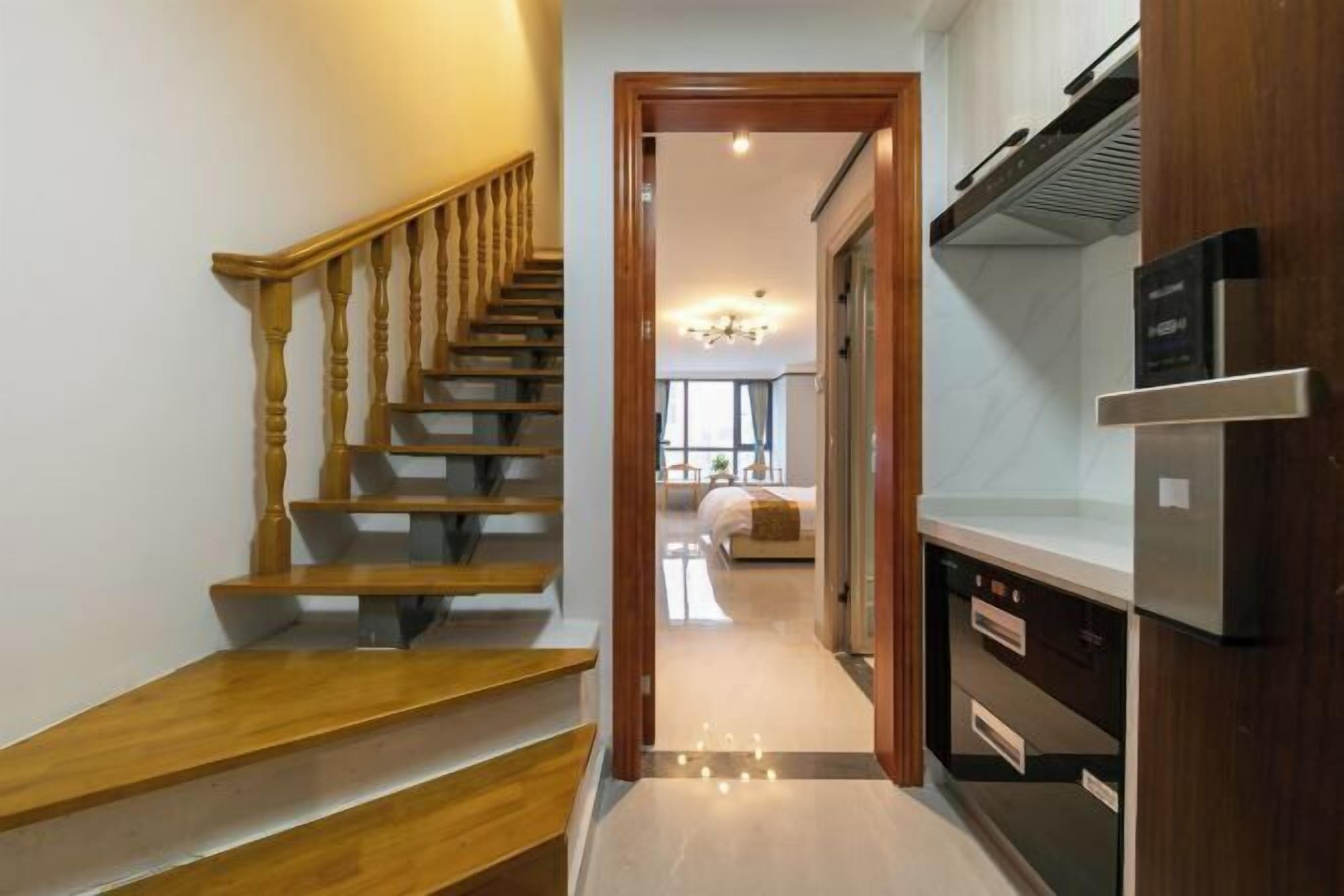 Eine moderne Küche mit eingebautem Backofen und einer Holztreppe, die zu einem Schlafzimmer führt.