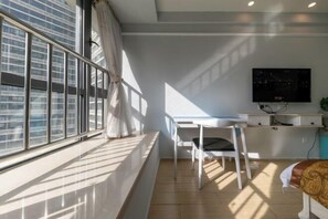 A modern room with a large window, a desk, a chair, and a television. - Gelandi Holiday Apartment (Haikou)