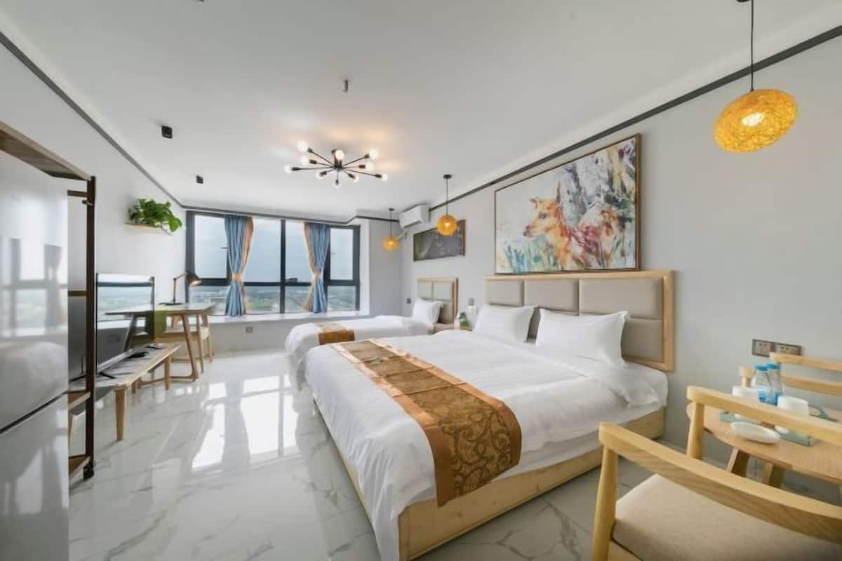 A modern hotel room with a large bed, a desk, and a view of the city.