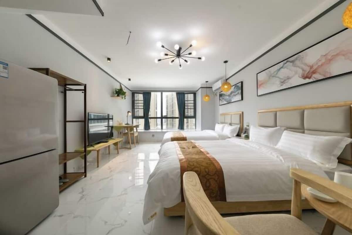 A modern hotel room with a large bed, a desk, a television, and a view of the city.