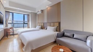 Ein Hotelzimmer mit zwei Betten, einer Couch, einem Fernseher und einem Balkon.