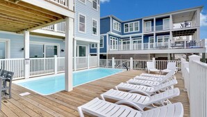 A multi-level building with a pool and lounge chairs. - Spacious oceanfront 7-bedroom home on Oak Island, perfect for large gatherings. (Oak Island)