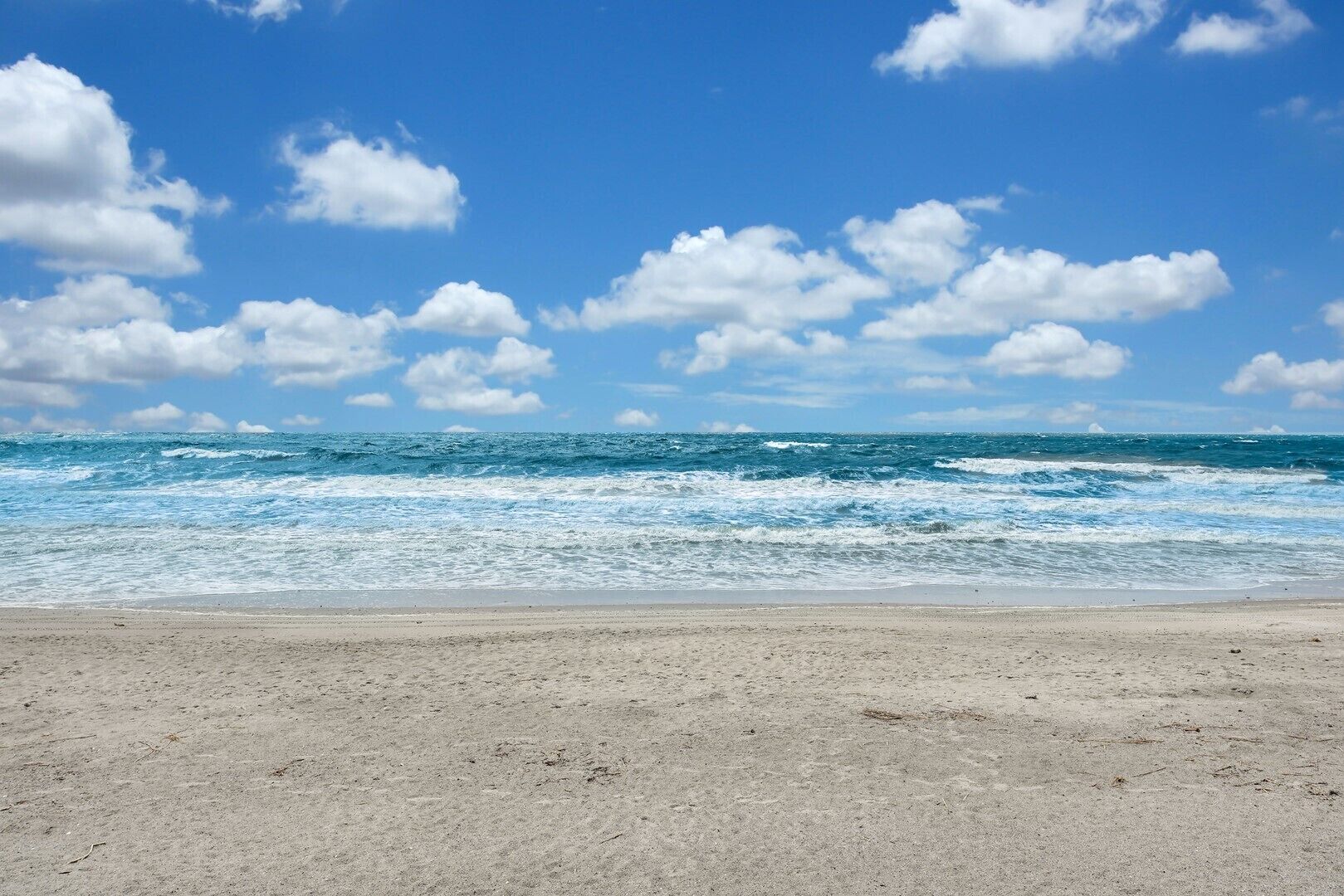 Ein Strand mit sandigem Ufer und dem Meer im Hintergrund.