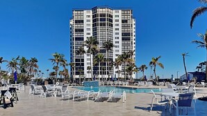 A hotel with a pool area, lounge chairs, and palm trees. - Ocean Harbor by Distinctive Beach Rentals (Fort Myers Beach)