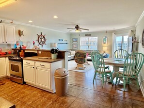 A spacious kitchen with a dining area, a ceiling fan, and a view of the outside.