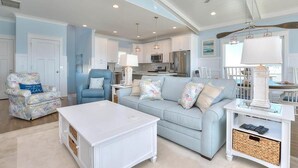 A spacious living room with a light blue sofa, a white coffee table, and a ceiling fan. - Oceanfront Dory: Spacious 5BR, 4BA home in Oak Island, perfect for 10 guests. (Oak Island)
