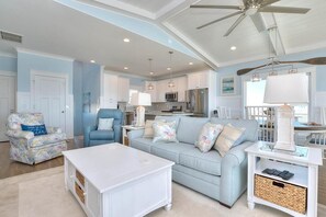 A spacious living room with a light blue sofa, a white coffee table, and a ceiling fan.