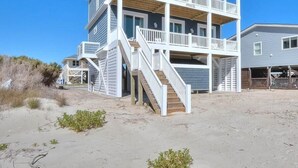 A two-story beachfront house with a balcony, a staircase, and a garage. - Oceanfront Dory: Spacious 5BR, 4BA home in Oak Island, perfect for 10 guests. (Oak Island)