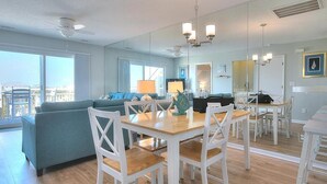 Un salon moderne avec une table à manger en bois, des chaises blanches et un canapé bleu.
