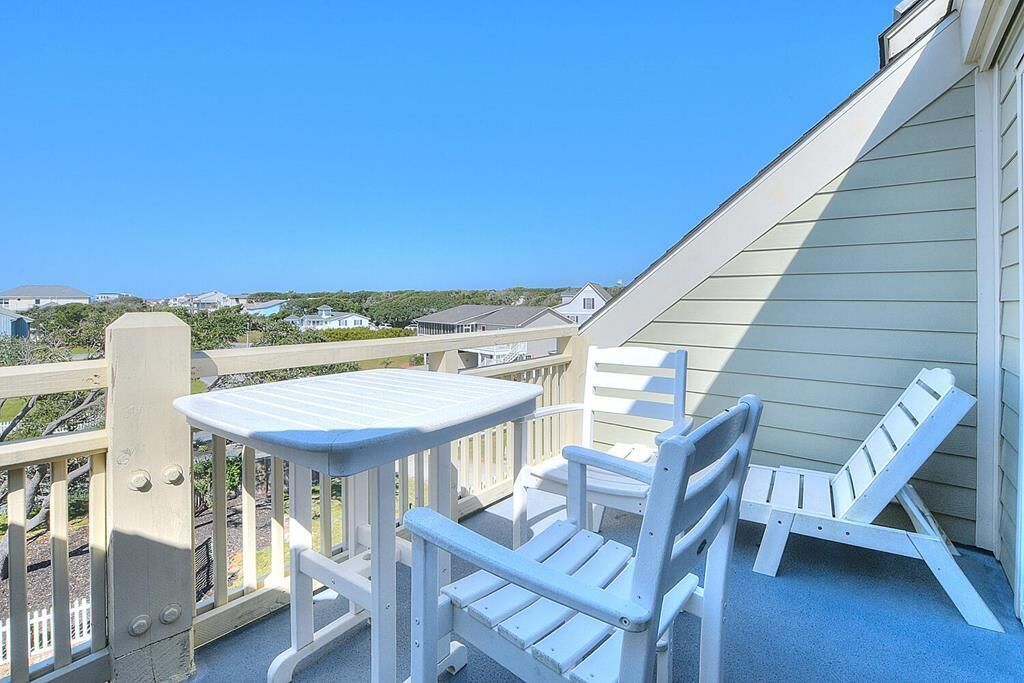 Een balkon met een tafel en twee stoelen, met uitzicht op een woonwijk.