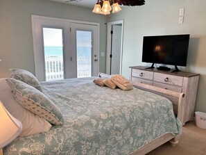 Een slaapkamer met een bed, een televisie, een dressoir en een balkon met uitzicht.