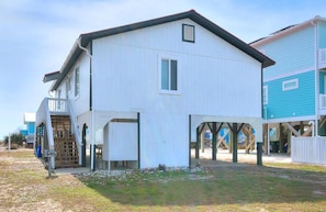 A two-story building with a white exterior and a red roof. It features a small window and a door.