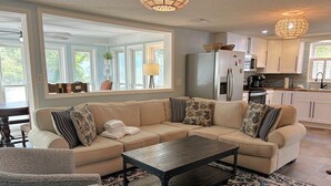 Ein modernes Wohnzimmer mit einer Eckcouch, einem Couchtisch und einem gemusterten Teppich.