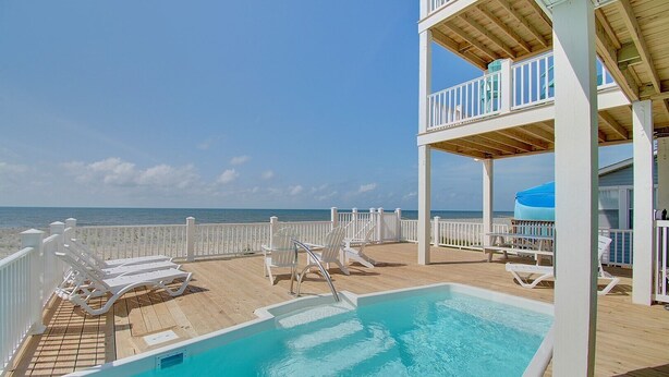 A pool area with lounge chairs and a view of the ocean. - Experience oceanfront luxury at AfterDune Delight, Oak Island's ideal getaway for 20 guests. (Oak Island)