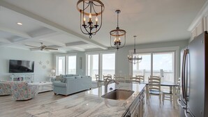 A spacious kitchen with a large island, modern appliances, and a view to the outside. - Experience oceanfront luxury at AfterDune Delight, Oak Island's ideal getaway for 20 guests. (Oak Island)