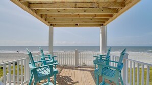 A wooden deck with two turquoise Adirondack chairs facing a beach. - Experience oceanfront luxury at AfterDune Delight, Oak Island's ideal getaway for 20 guests. (Oak Island)