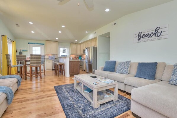 A modern living room with a beige sofa, a coffee table, and a patterned rug.