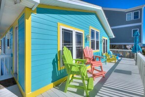 A colorful house with a porch featuring Adirondack chairs.
