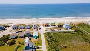 An aerial view of a coastal residential area with houses and a beach.
