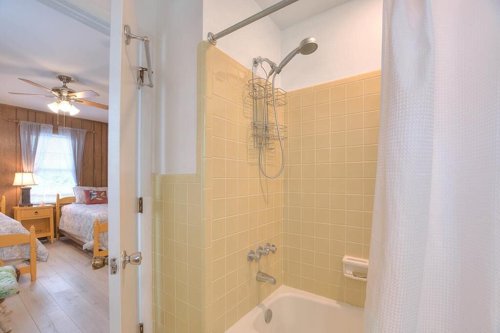 A bathroom with a bathtub, shower, and a ceiling fan.