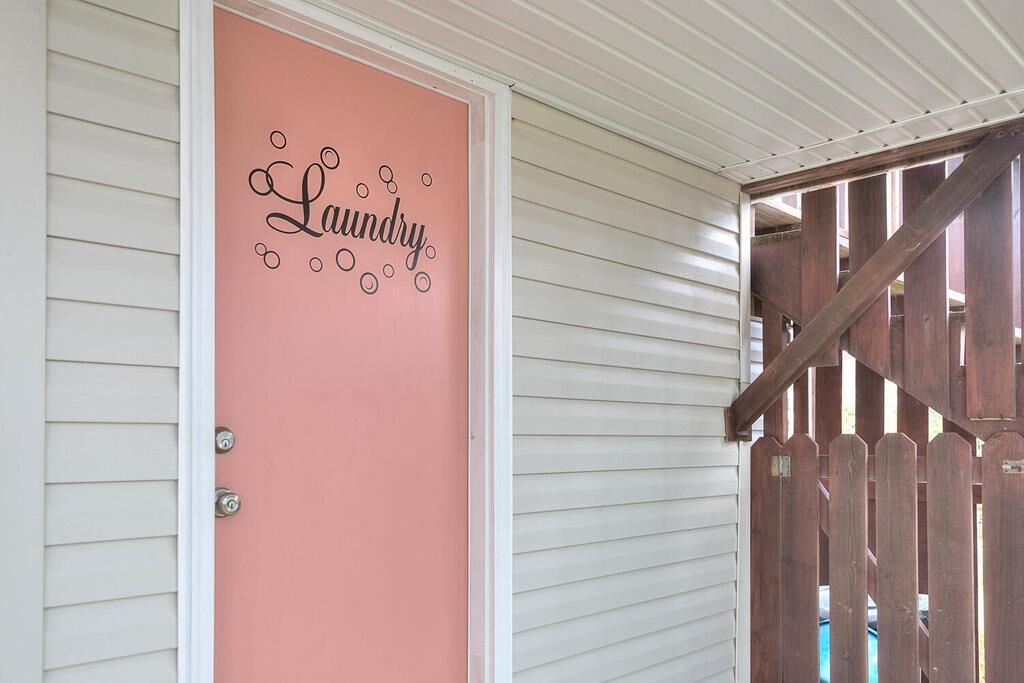 Una puerta con un letrero rosa que dice 'Laundry' y un portón de madera.