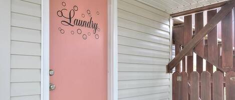 Una puerta con un letrero rosa que dice 'Laundry' y un portón de madera.