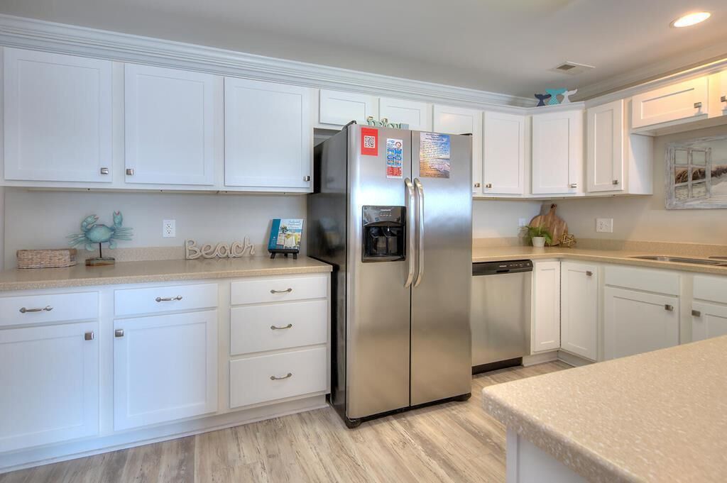 Una cocina con armarios blancos, un refrigerador de acero inoxidable y un lavavajillas.