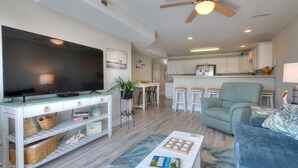 Un salon moderne avec un téléviseur à écran plat, une table basse, un canapé et un ventilateur de plafond.