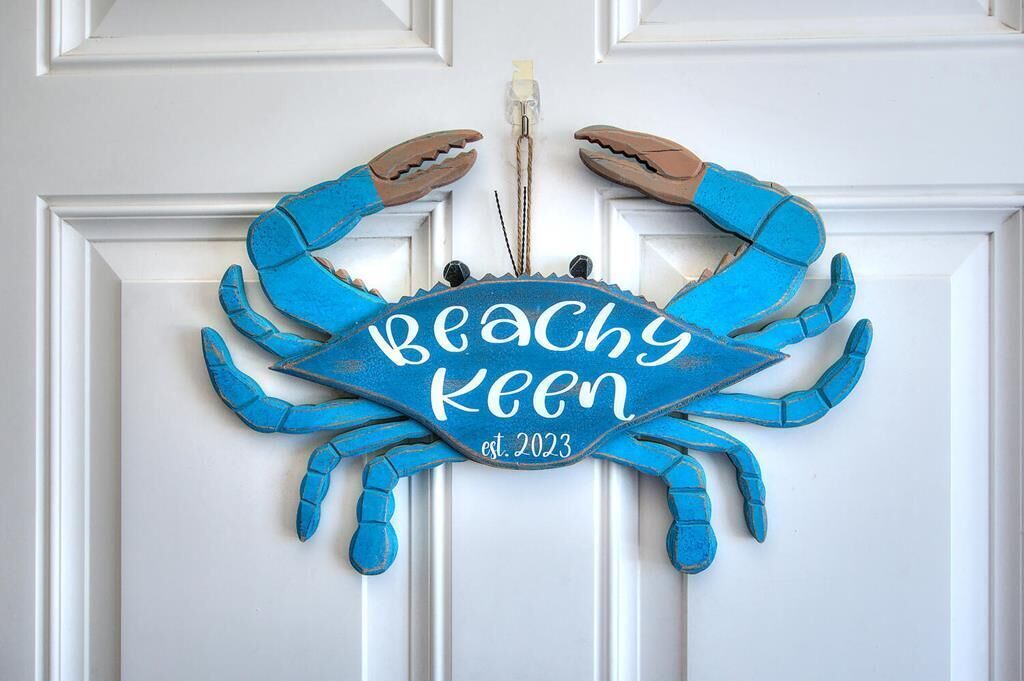 A blue crab decoration with the text "Beachy Keen est. 2023" on a white door.