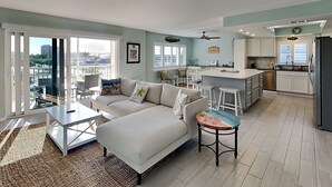 A modern apartment with a living room, dining area, and kitchen. - Sand Caper by Distinctive Beach Rentals (Fort Myers Beach)