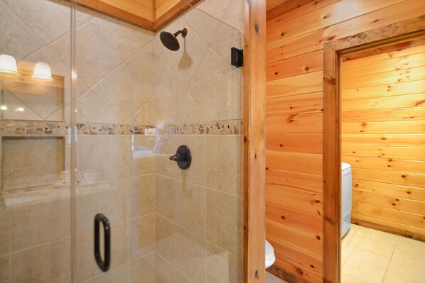 Ein Badezimmer einer Holzhütte mit Dusche, Toilette und Fliesenboden.