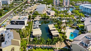 An aerial view of a marina with boats docked, surrounded by buildings and a beach in the background. - Santa Maria by Distinctive Beach Rentals (Fort Myers Beach)