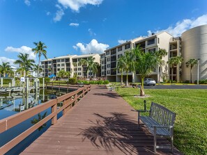 A waterfront hotel with a wooden boardwalk, palm trees, and a parking area. - Santa Maria by Distinctive Beach Rentals (Fort Myers Beach)