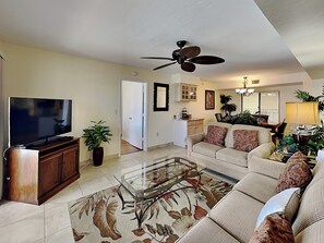 A living room with a television, sofa, coffee table, and ceiling fan. - Santa Maria by Distinctive Beach Rentals (Fort Myers Beach)