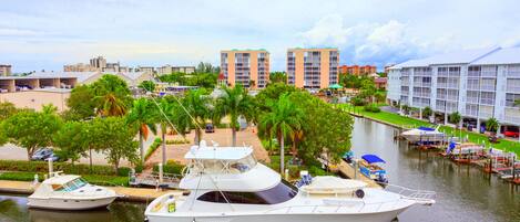 A marina with several boats docked, surrounded by palm trees and buildings.